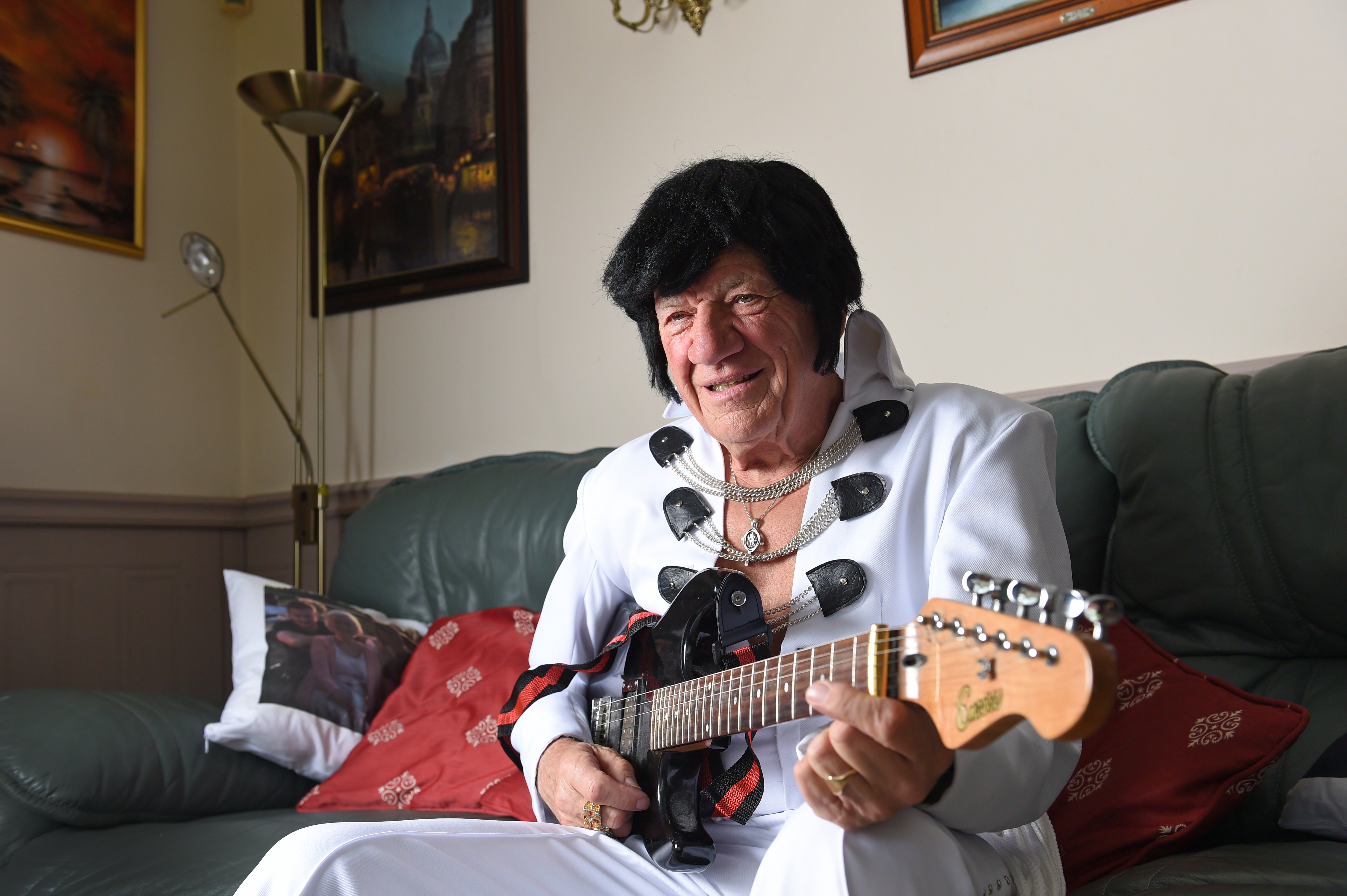 A man dressed as Elvis holding a guitar