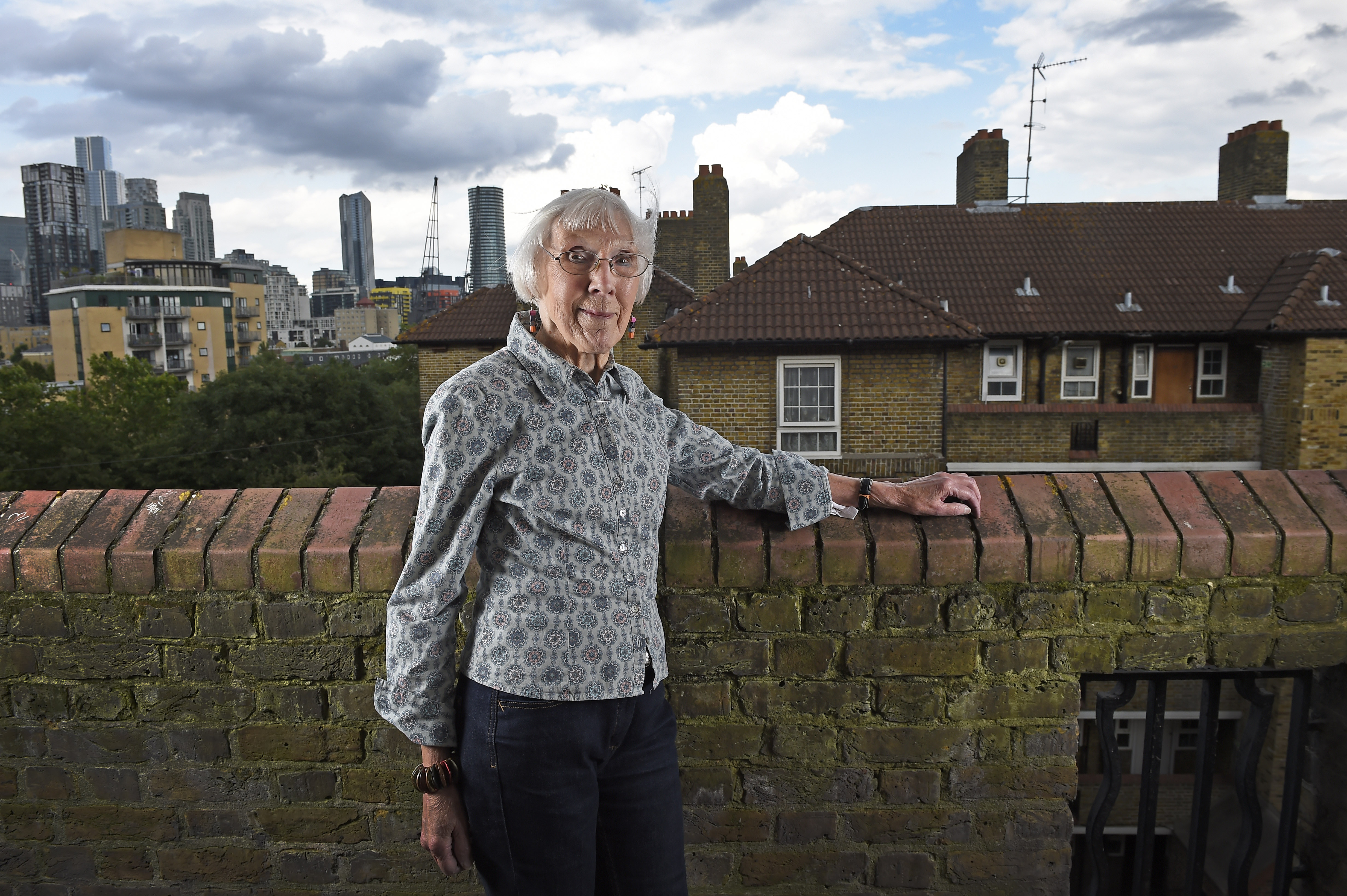 A woman standing by a wall with skyscrapers in distance