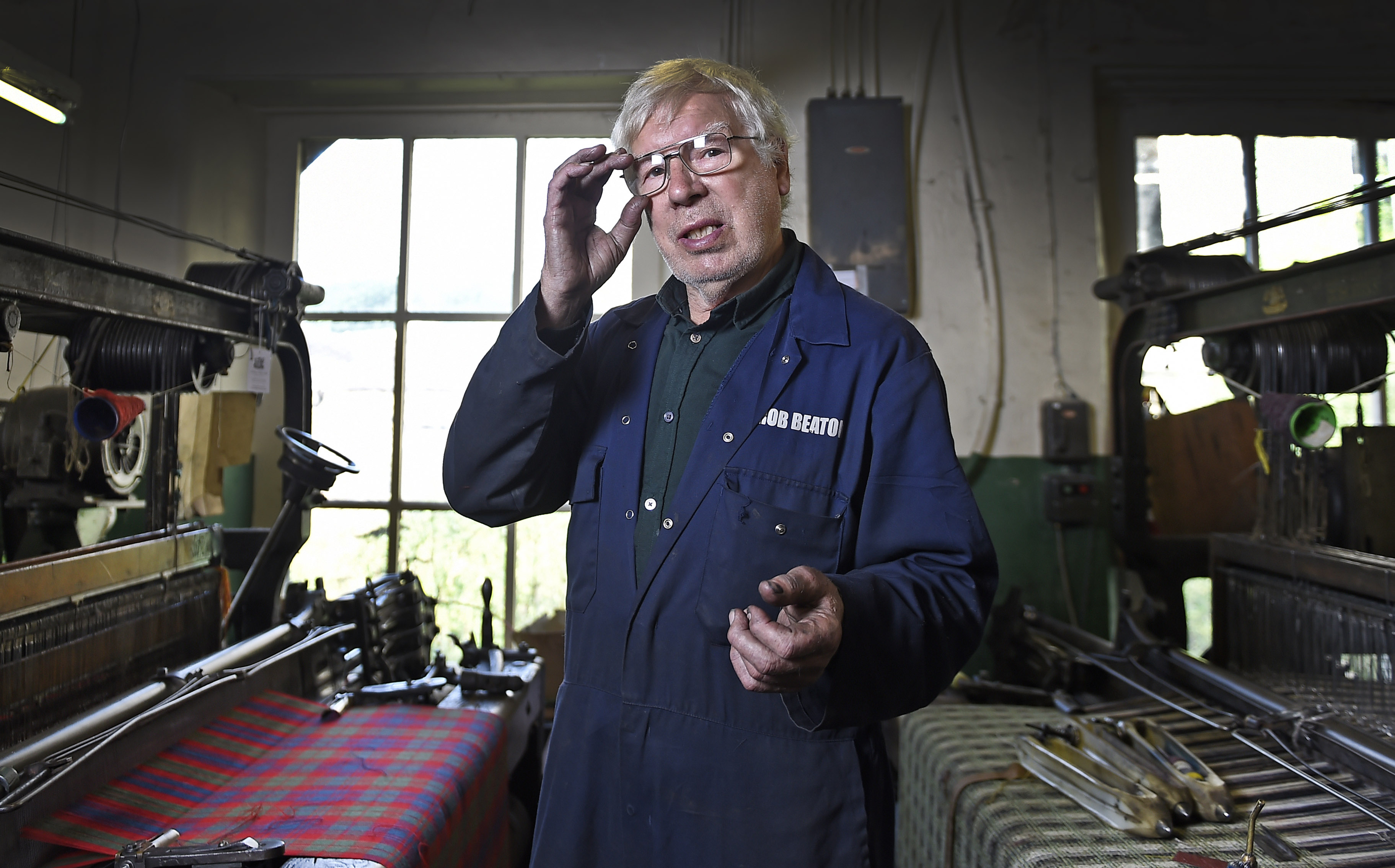 man touching glasses in tartan cloth factory