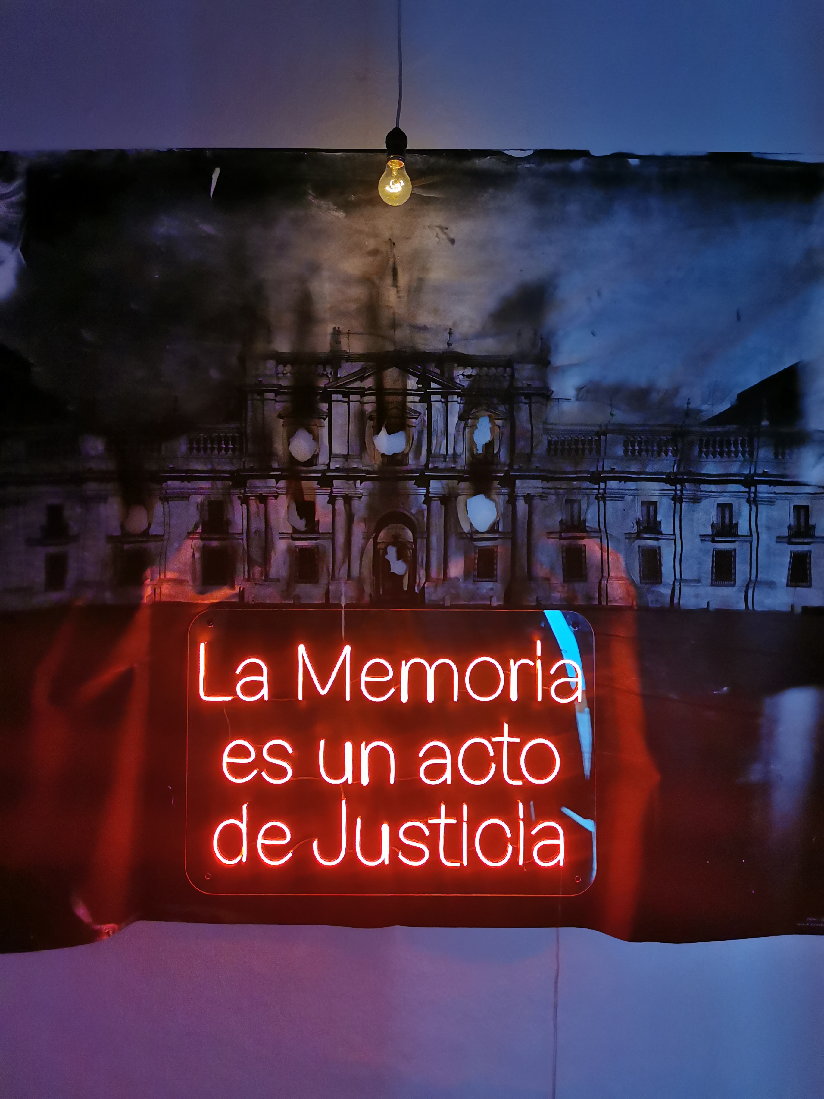 Red neon text saying "La Memoria en un acto de Justicia"