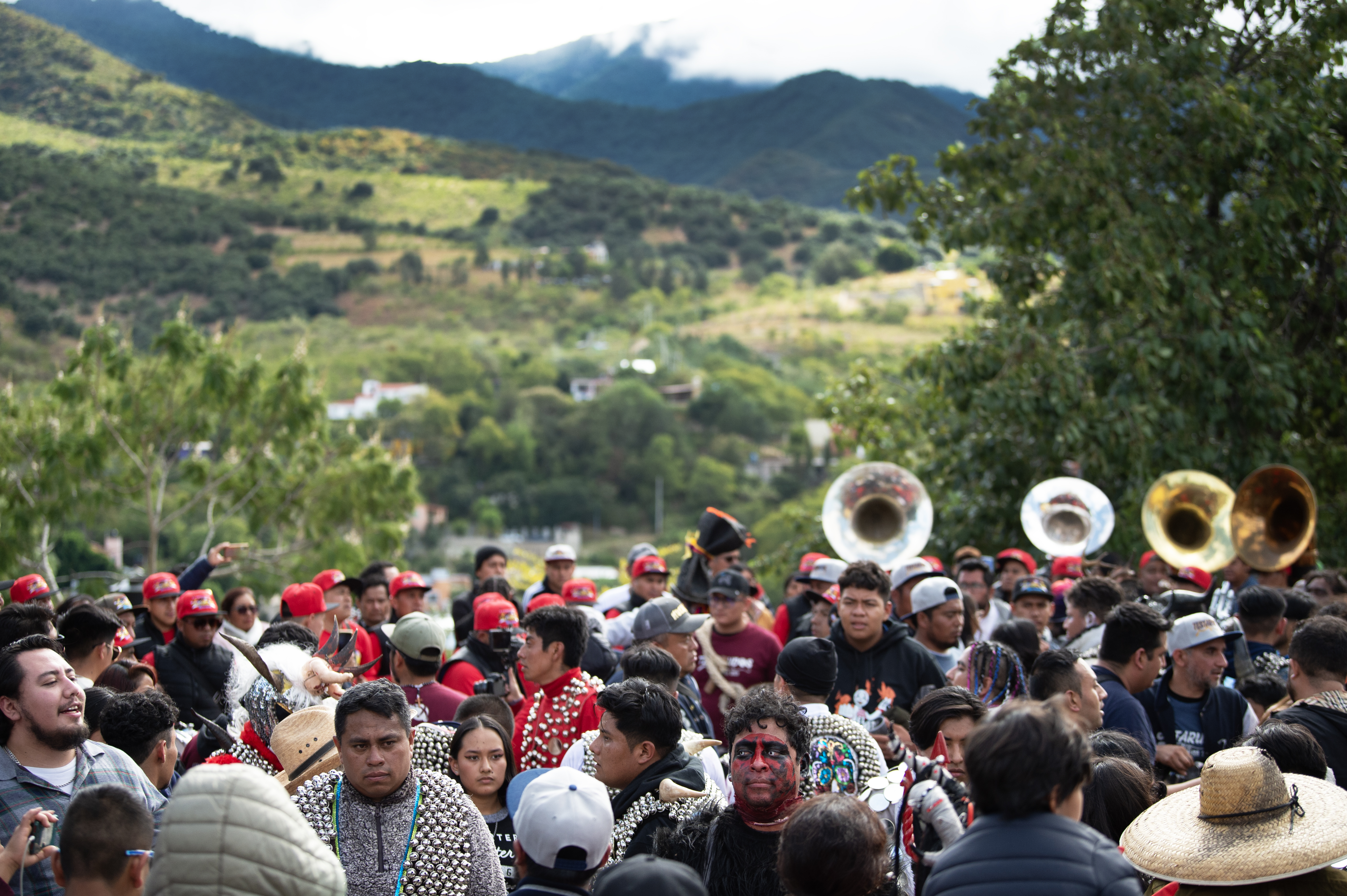 people in costuem and playing instruments with green hills behind the in the distance